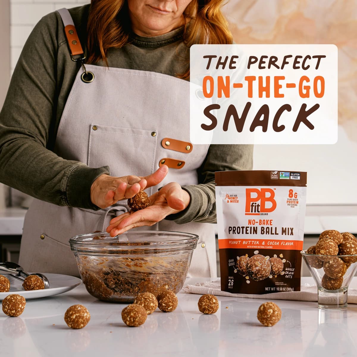 A person rolling a PBfit Protein Ball Cocoa in a circle with other protein balls around the bowl.