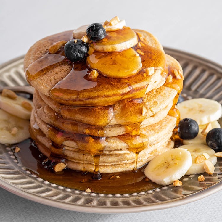 Stack of pancakes with banana slices and blueberries