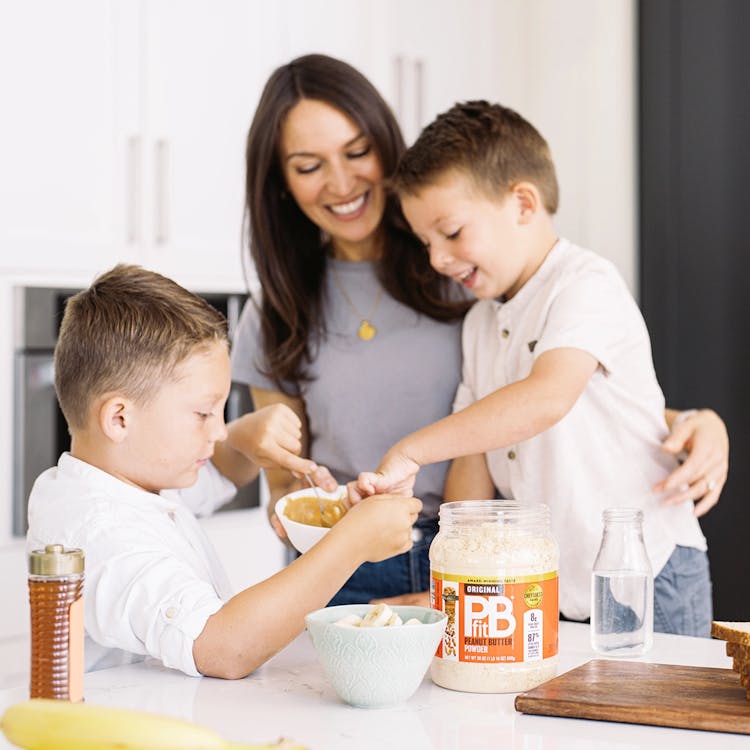 Mother making PBfit Peanut Butter Powder into spread with kids